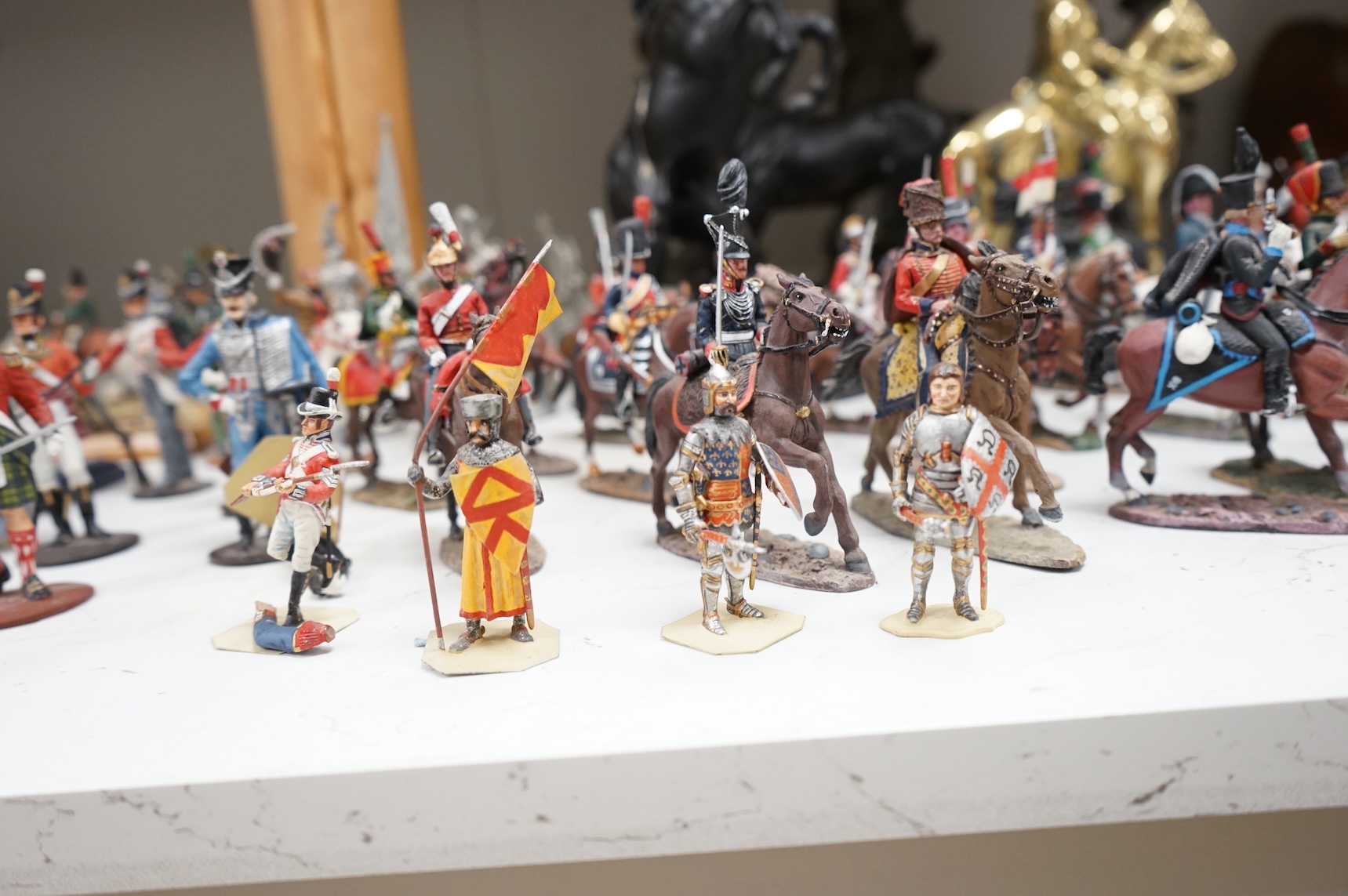 A pair of spelter figures a brass door stop two models of horses two other figures and a large group of toy soldiers. Tallest 45cm.